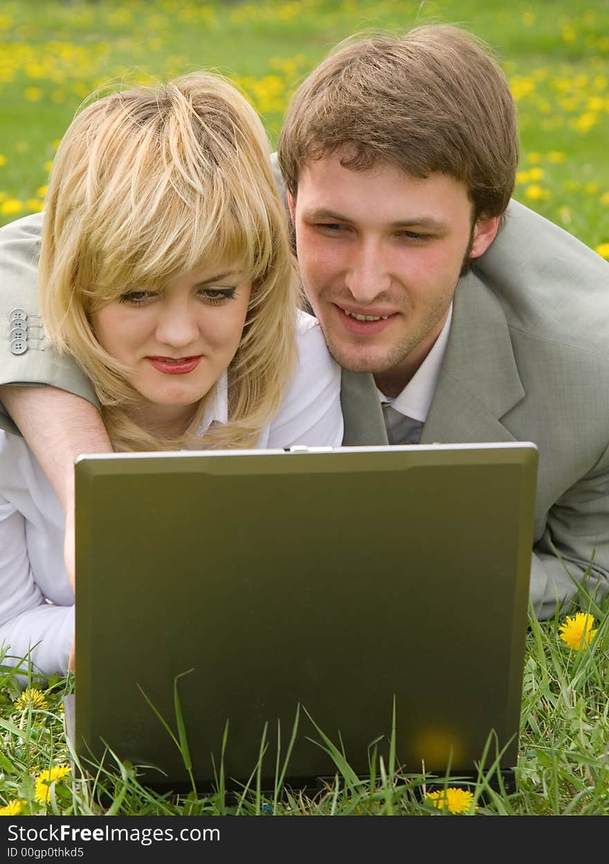 Young cheerful couple working on laptop at outdoor environment. Young cheerful couple working on laptop at outdoor environment