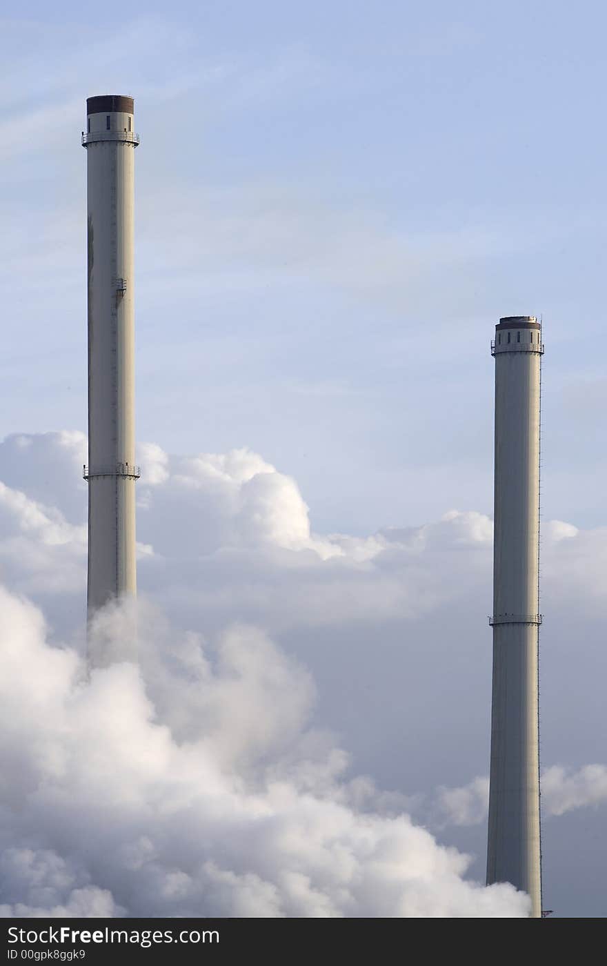 Two industrial chimneys amidst clouds