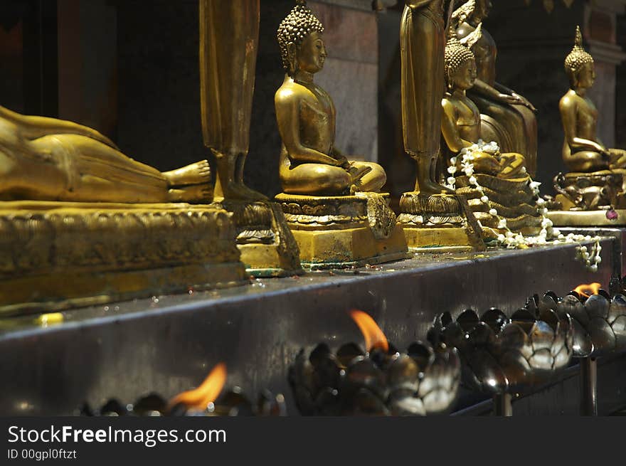 Buddha statues with lotus lamps on their front. Garland as an offertory. Butter lamps are burning. Doi Suthep temple, Chiang Mai Province, Thailand. Buddha statues with lotus lamps on their front. Garland as an offertory. Butter lamps are burning. Doi Suthep temple, Chiang Mai Province, Thailand