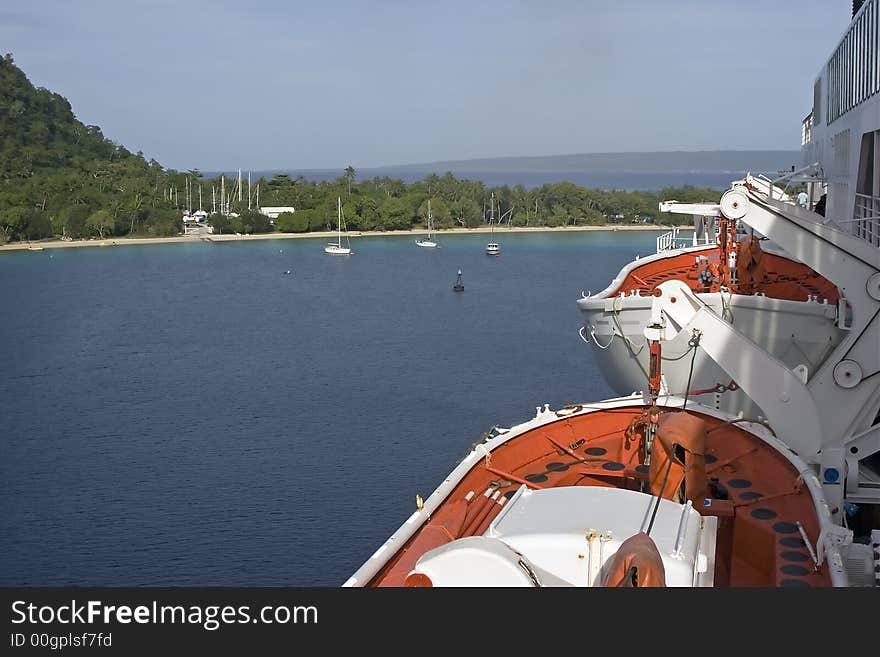 Cruise ship leaving tropical island harbor, showing lifeboats. Cruise ship leaving tropical island harbor, showing lifeboats.