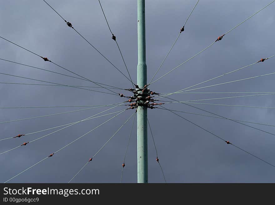 A green pole with wires going every which way. A green pole with wires going every which way