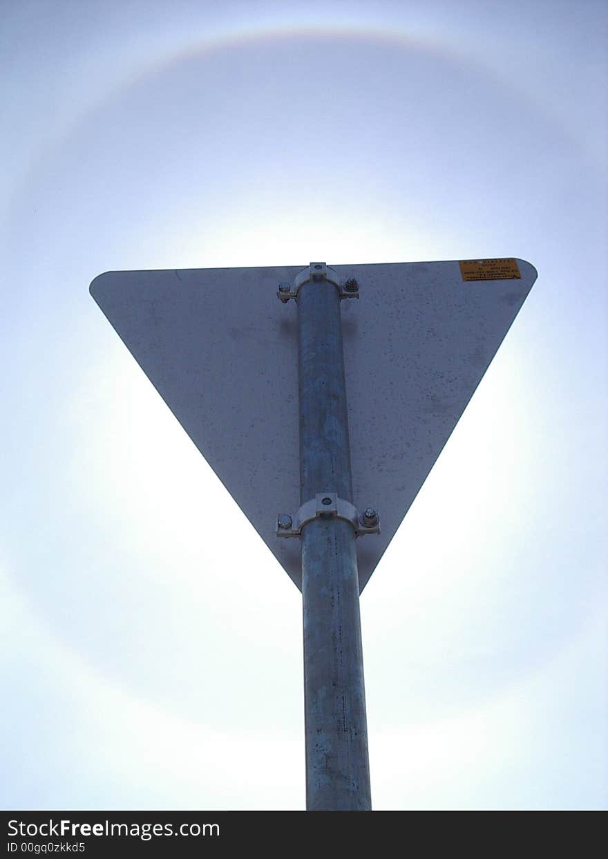 The rainbow ring around the sun as visible behind the triangle sign post. The rainbow ring around the sun as visible behind the triangle sign post