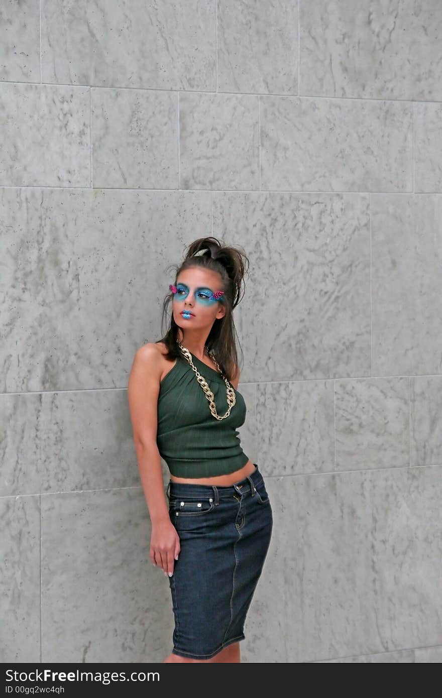 A young dark makeup model posing against wall. A young dark makeup model posing against wall