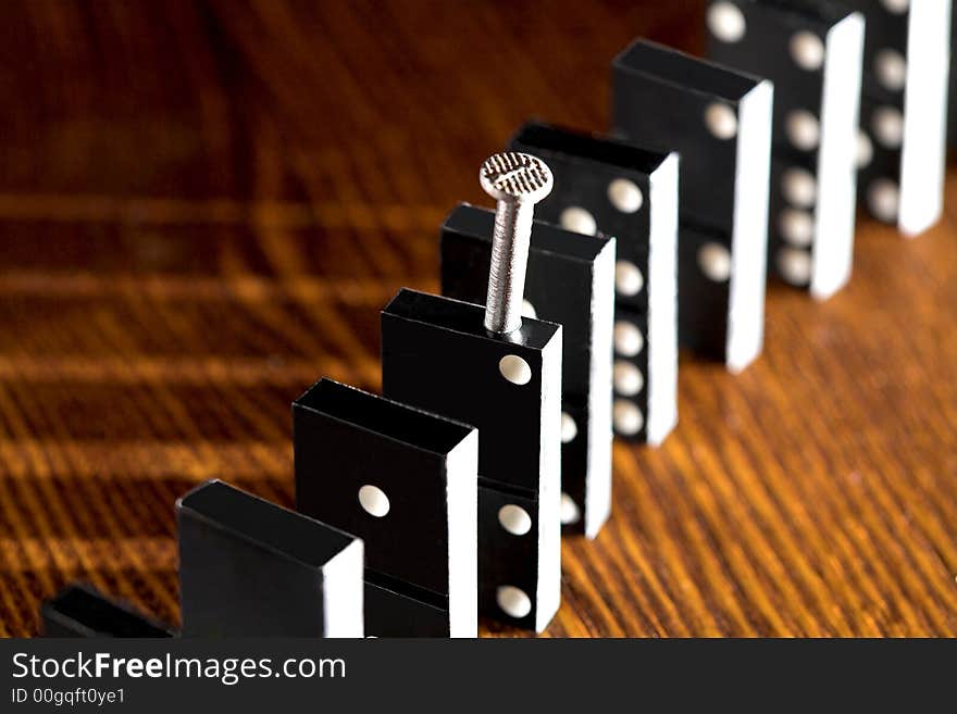 Nail and row of dominoes on a table, (studio, halogen light and flash). Nail and row of dominoes on a table, (studio, halogen light and flash).