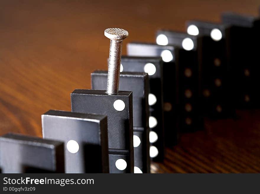 Nail and row of dominoes on a table, (studio, halogen light and flash). Nail and row of dominoes on a table, (studio, halogen light and flash).