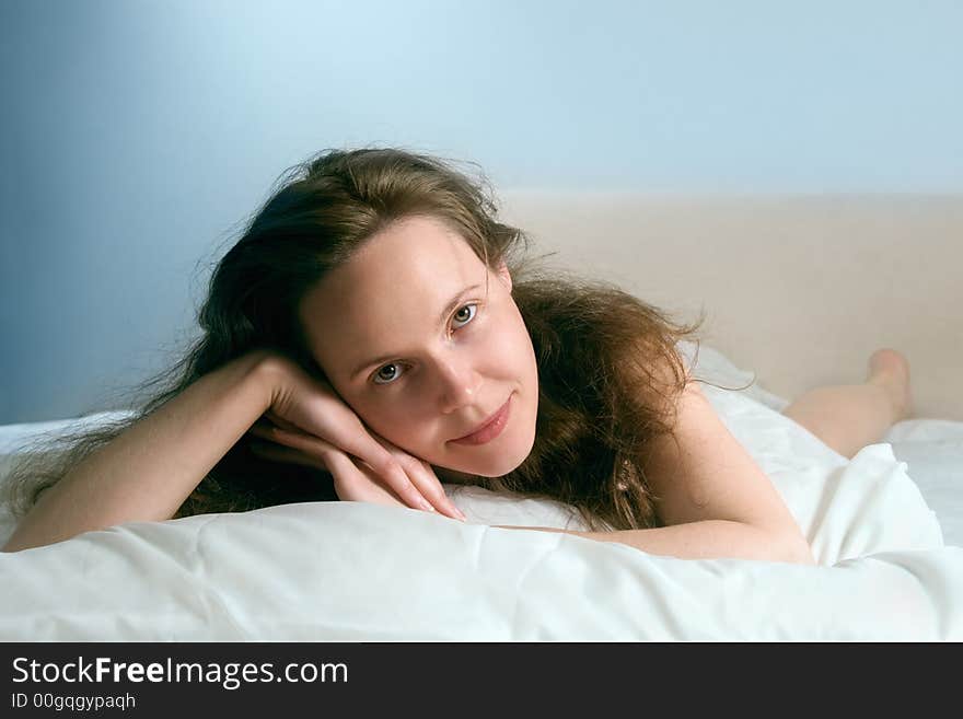 Portrait of a young awakened smiling woman lying on a bed. Portrait of a young awakened smiling woman lying on a bed