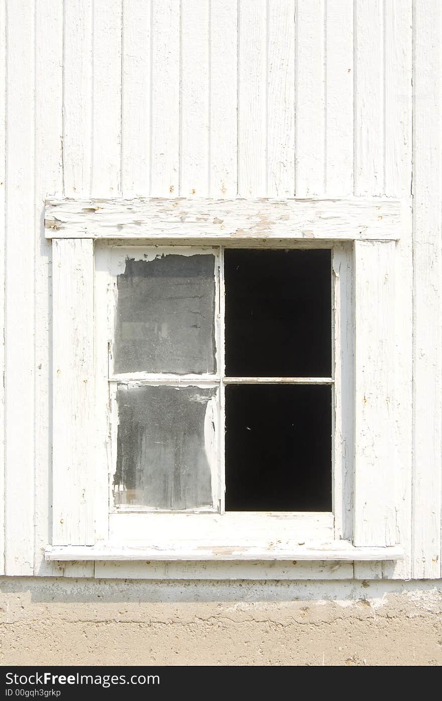 One of the windows of an old white barn is broken. One of the windows of an old white barn is broken.