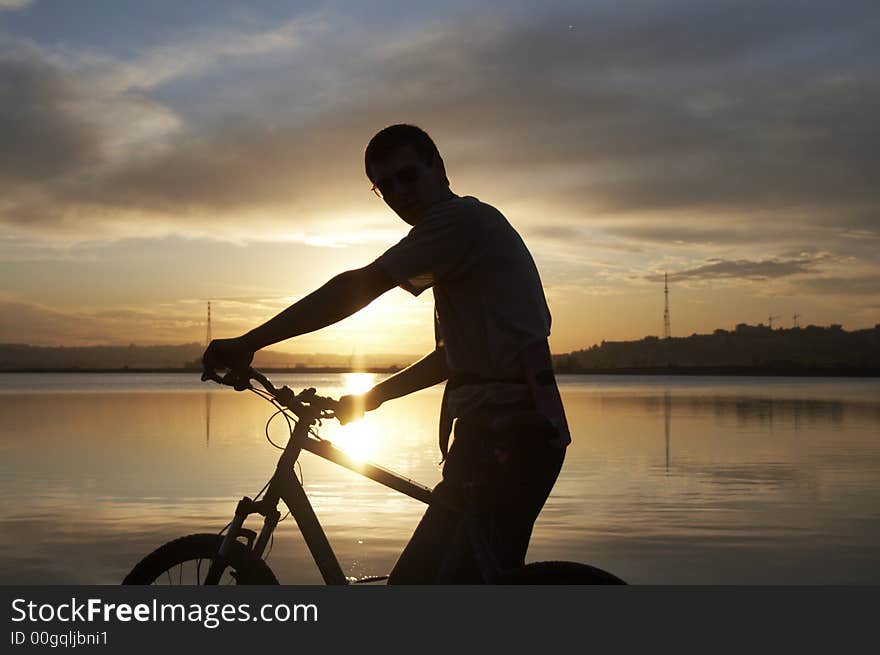 Man with bike with lake on the background. Sunset. Man with bike with lake on the background. Sunset.