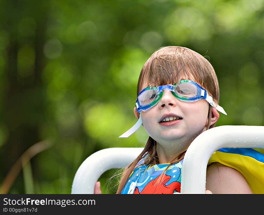 Cute small girl sitting on pool ladder wearing goggles - ears folded under straps. Cute small girl sitting on pool ladder wearing goggles - ears folded under straps.