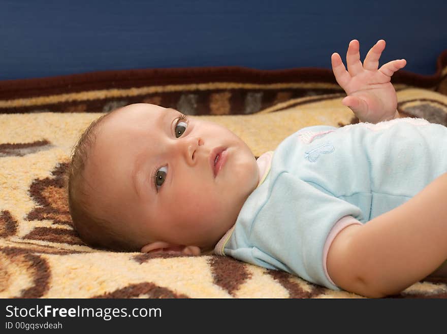 Cute baby boy sitting on his back in bed