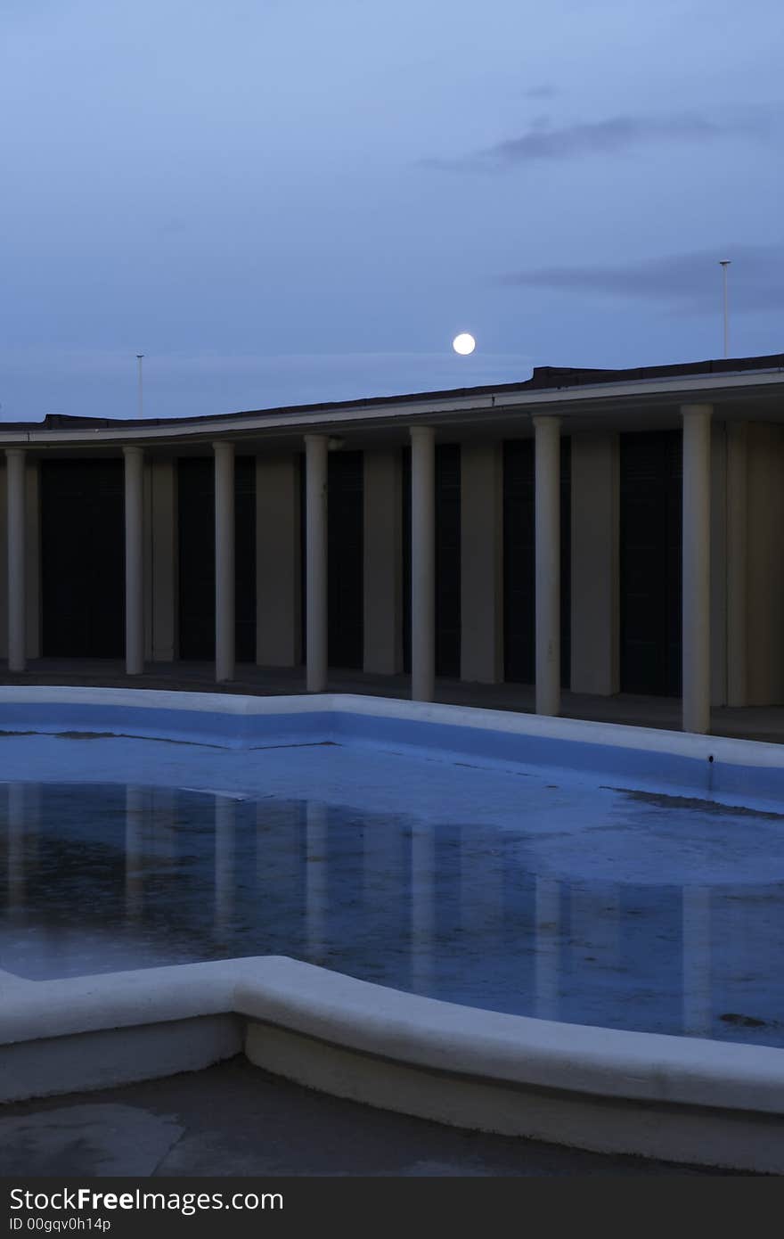 Early morning at Deauville bathouse of the moviestars. The swimming pool with just a bit of water in it and the moon above  the colonade. Early morning at Deauville bathouse of the moviestars. The swimming pool with just a bit of water in it and the moon above  the colonade.