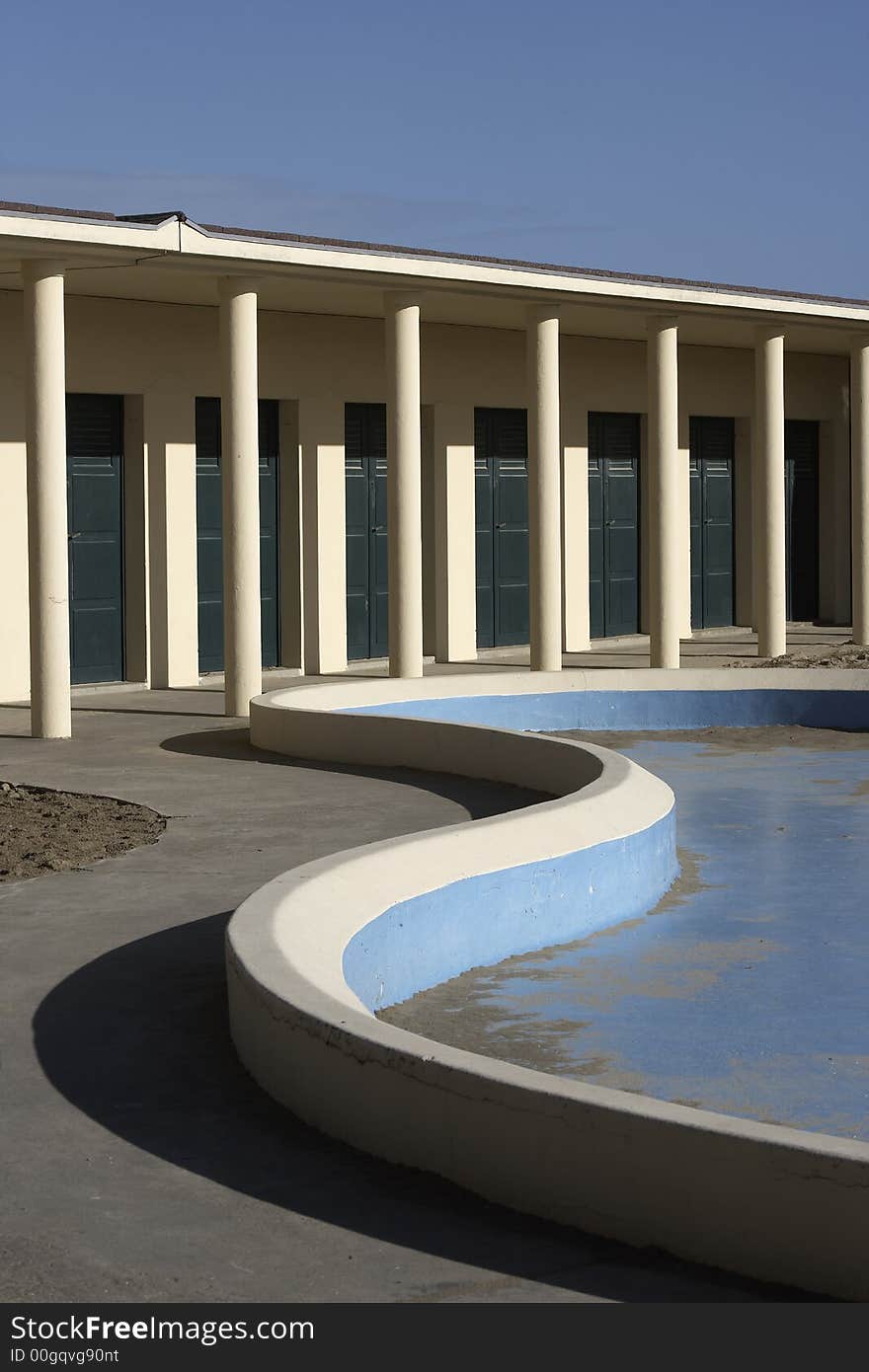 Famous beachhouse of the moviestars in Deauville,France. With a beautifull curve of the empty swimming pool in the front, arcade with green doors in the back at a sunny day. Famous beachhouse of the moviestars in Deauville,France. With a beautifull curve of the empty swimming pool in the front, arcade with green doors in the back at a sunny day.