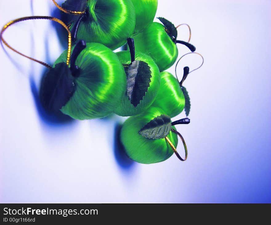 Green satin Christmas apples on the blue calm background.