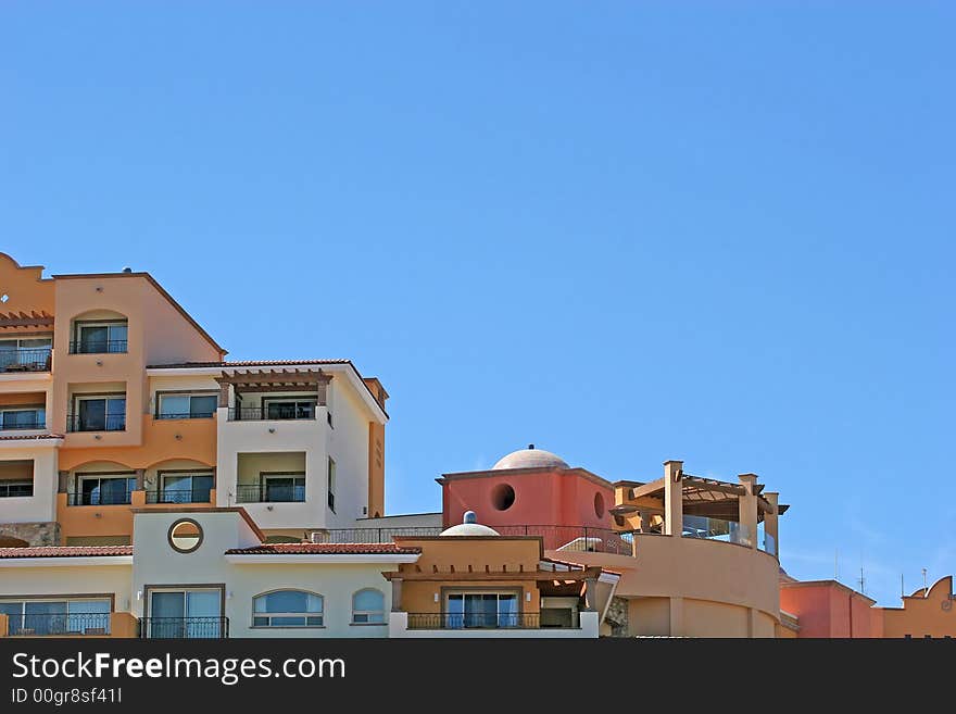 Multi colored condos on a hill against blue sky. Multi colored condos on a hill against blue sky