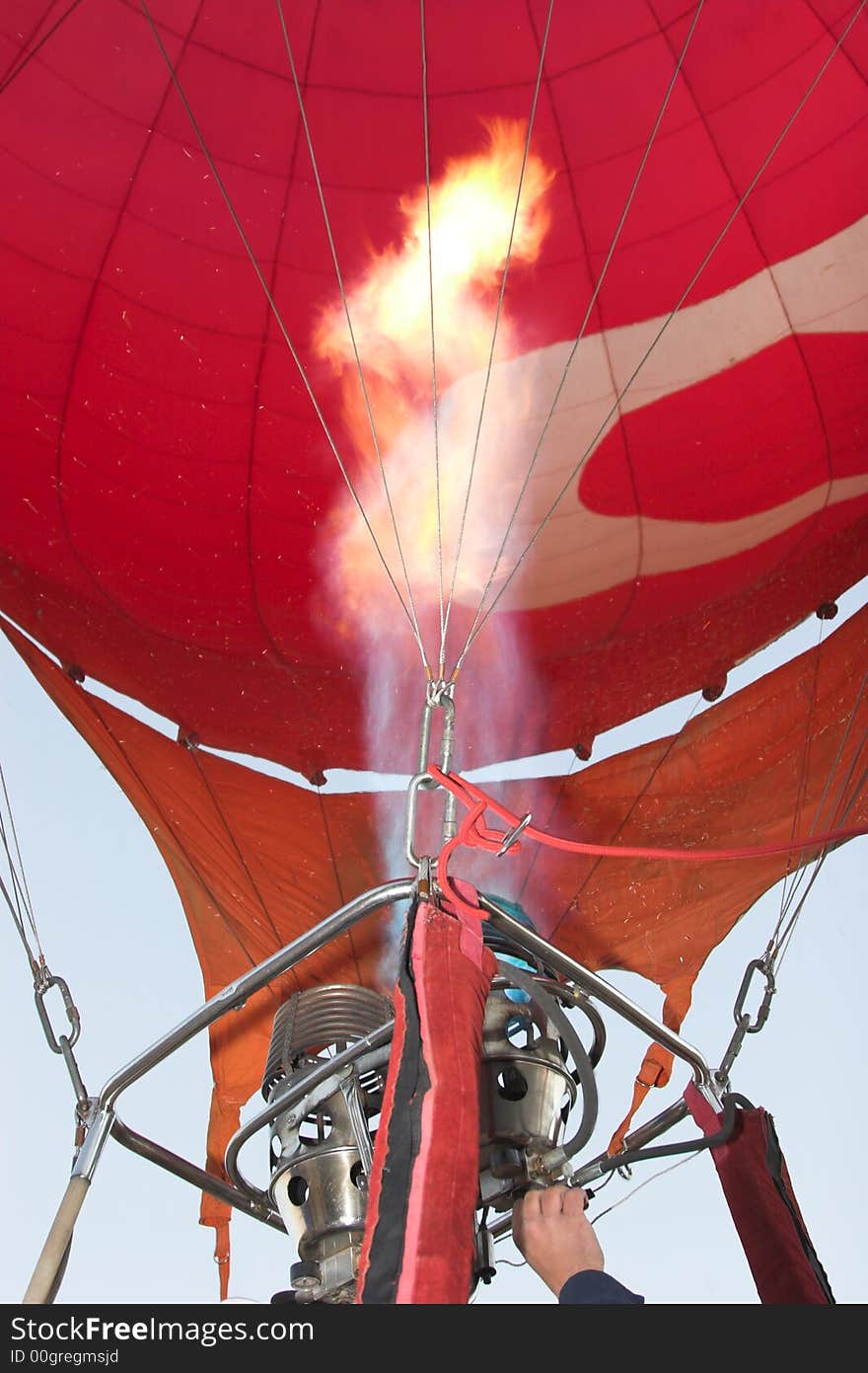 Balloonist busy burning propane to get balloon in the air. Balloonist busy burning propane to get balloon in the air