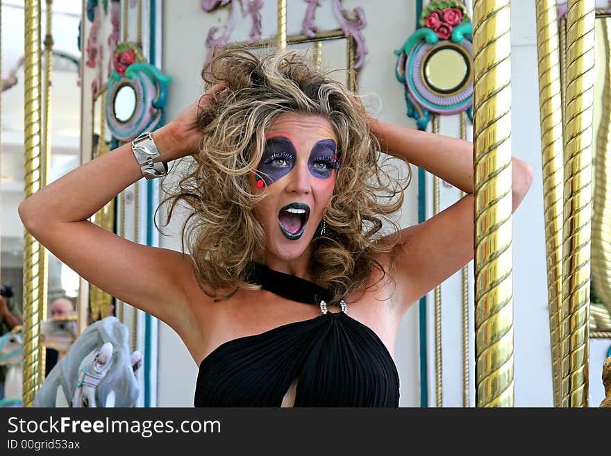 Model with wild makeup on a carousel screaming. Model with wild makeup on a carousel screaming