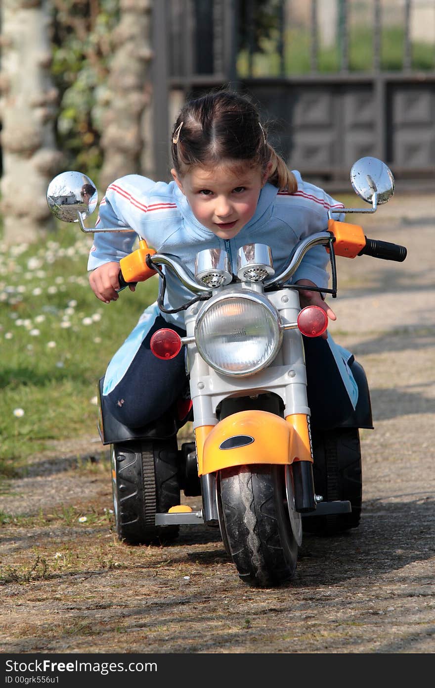 Female child playing with motor-cycle in the garden. Female child playing with motor-cycle in the garden