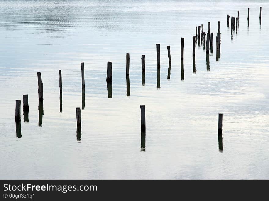 Some Wooden post  reflected on a lake