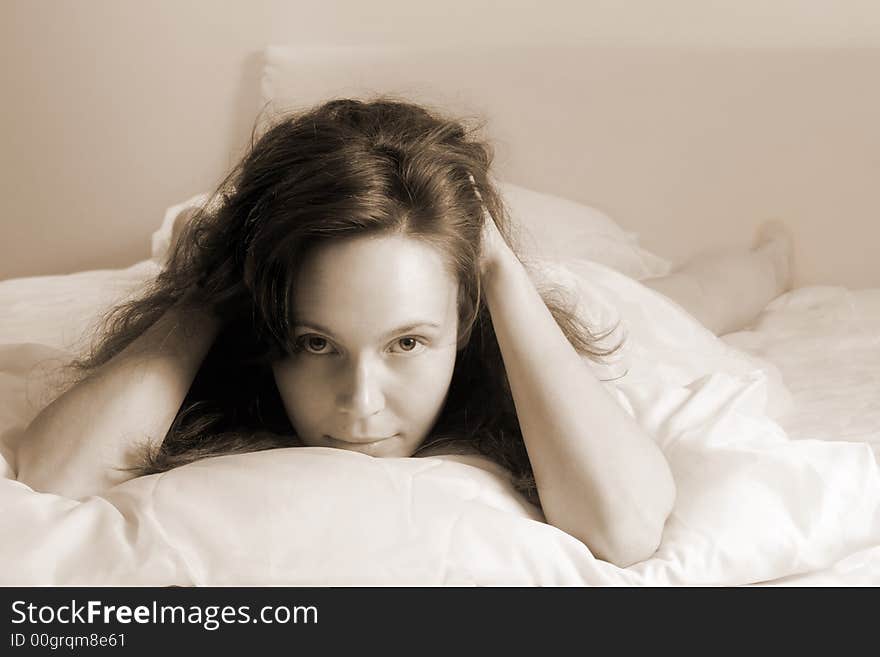 Portrait of young awakened girl lying on a bed(soft-focused+sepia toned). Portrait of young awakened girl lying on a bed(soft-focused+sepia toned)