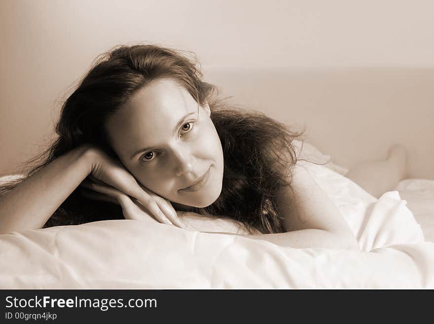 Portrait of a young awakened smiling woman lying on a bed(soft-focused+sepia toned). Portrait of a young awakened smiling woman lying on a bed(soft-focused+sepia toned)