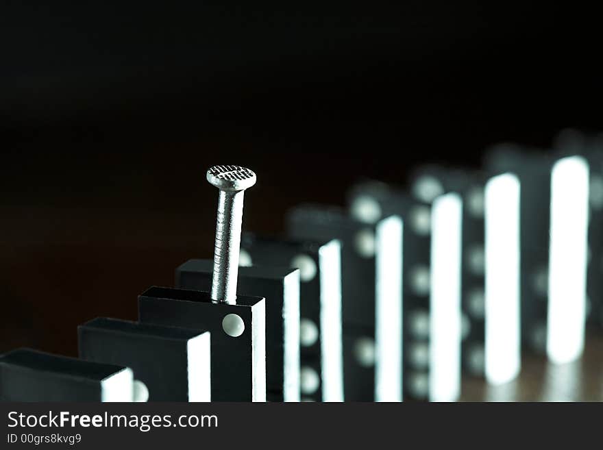 Nail and row of dominoes on a table, (studio, halogen light and flash). Nail and row of dominoes on a table, (studio, halogen light and flash).