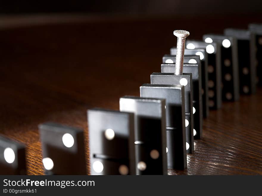 Nail and row of dominoes on a table, (studio, halogen light and flash). Nail and row of dominoes on a table, (studio, halogen light and flash).