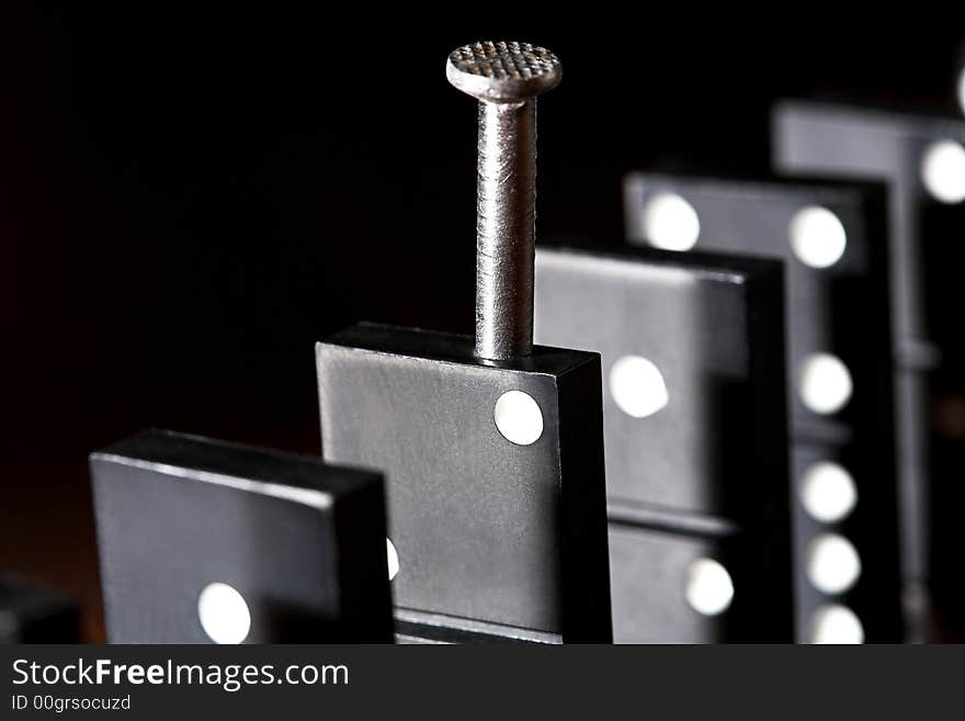 Nail and row of dominoes on a table, (studio, halogen light and flash). Nail and row of dominoes on a table, (studio, halogen light and flash).