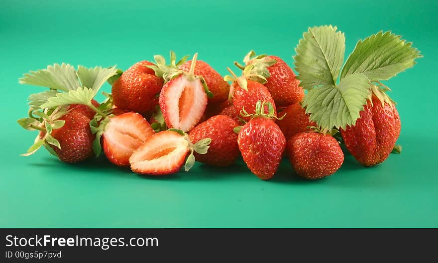 Some strawberries lay on a green background with a leaflet. Some strawberries lay on a green background with a leaflet