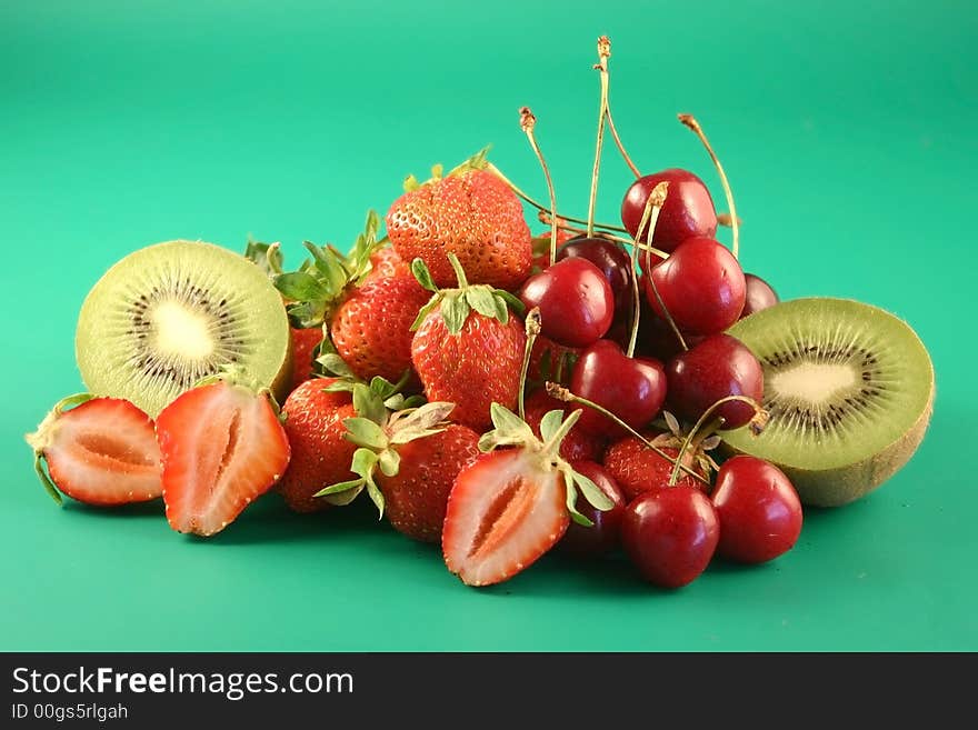 Strawberry and fruit is photographed on a green background