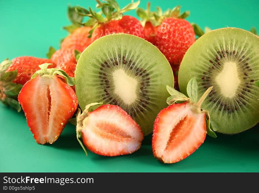 Strawberry and kiwi is photographed on a green background