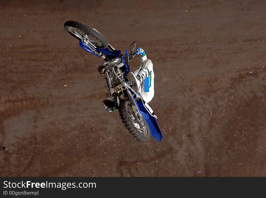 A freestyle moto-x rider goes through a trick during an indoor competition.