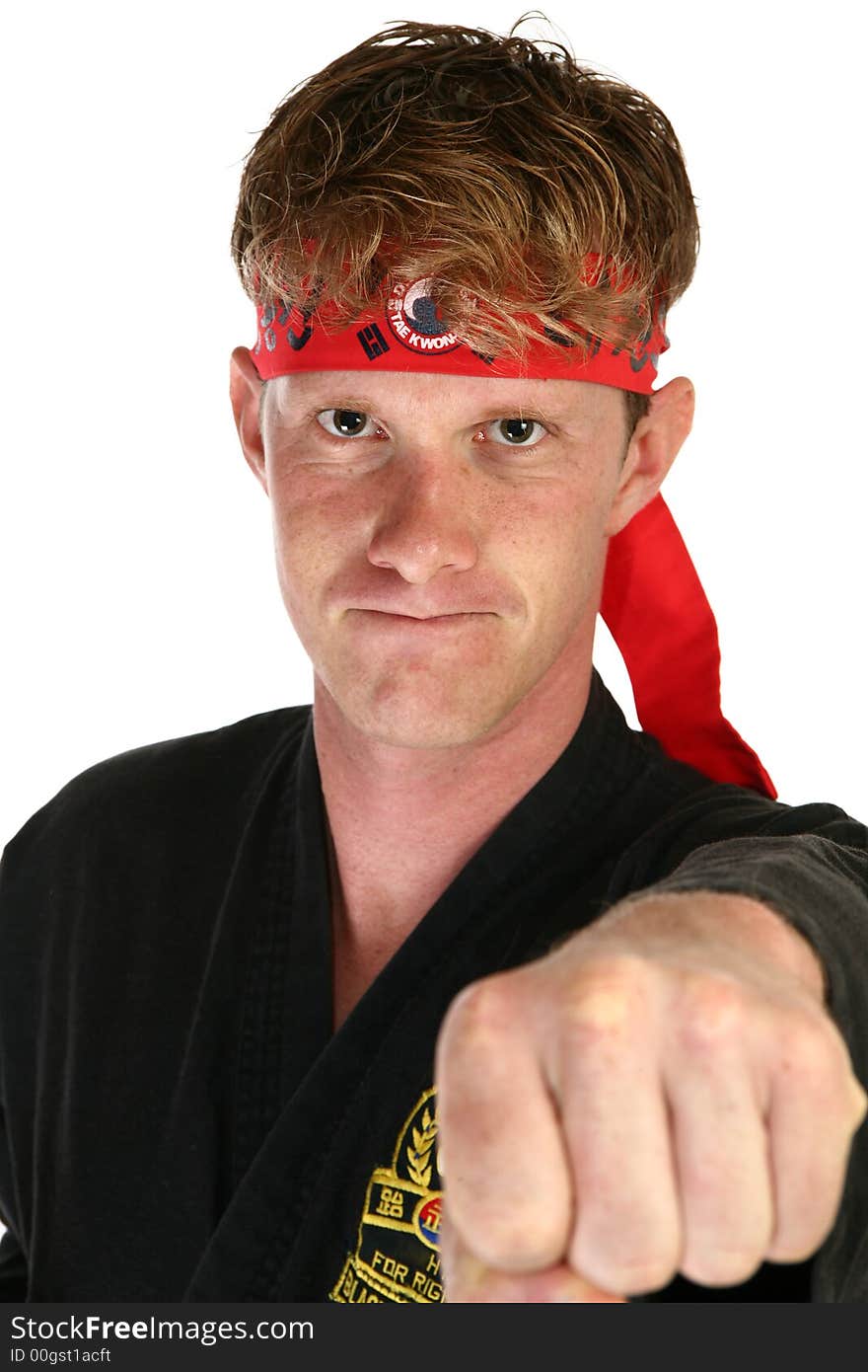 Attractive 30 something man in martial arts uniform punching towards camera.