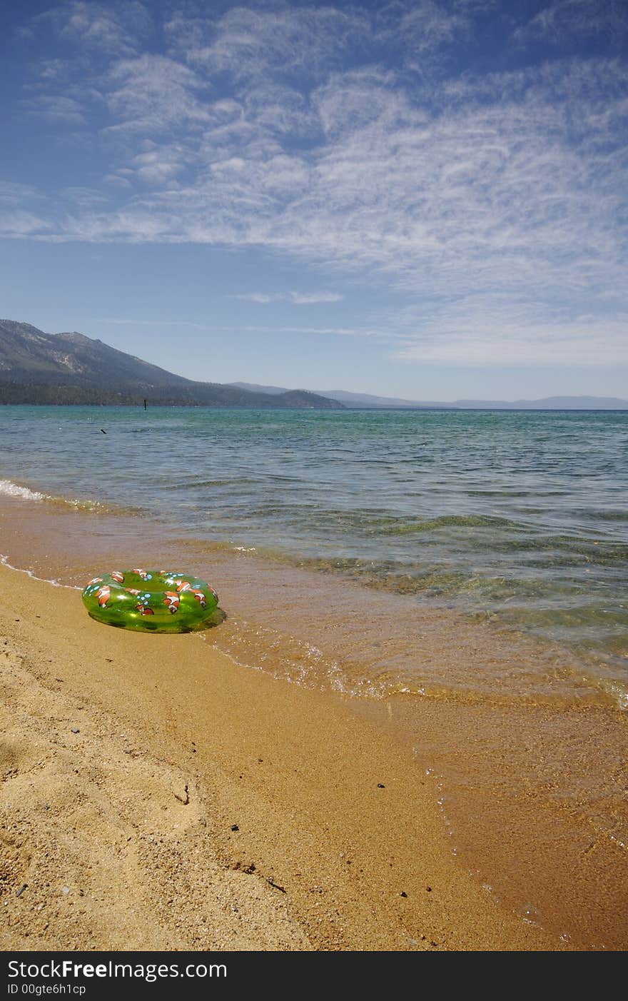 Childs toy livesave and waves from lake tahoe flowing over yellow sand. Childs toy livesave and waves from lake tahoe flowing over yellow sand