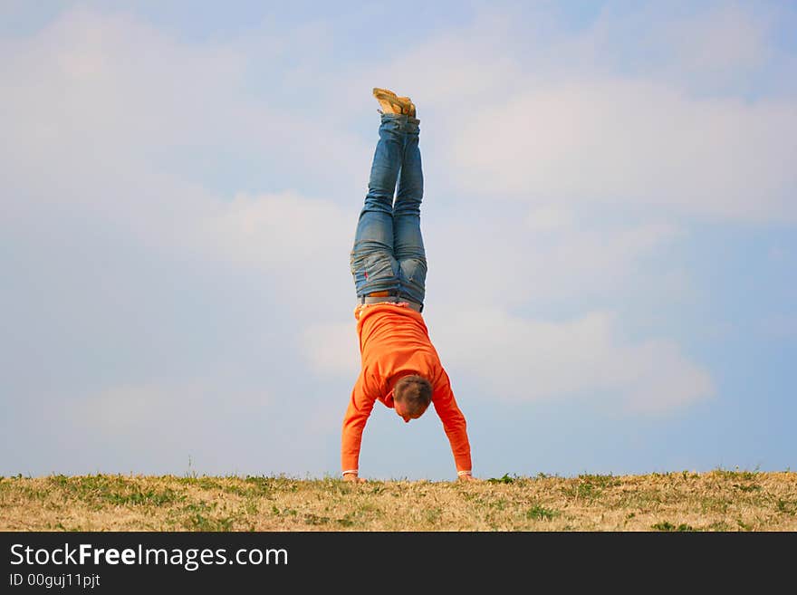 Man stand upside down against a cloudy sky