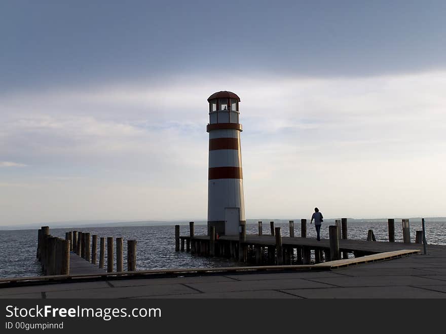 Lighthouse at an Austrian lake with a woman walking towards it. Lighthouse at an Austrian lake with a woman walking towards it