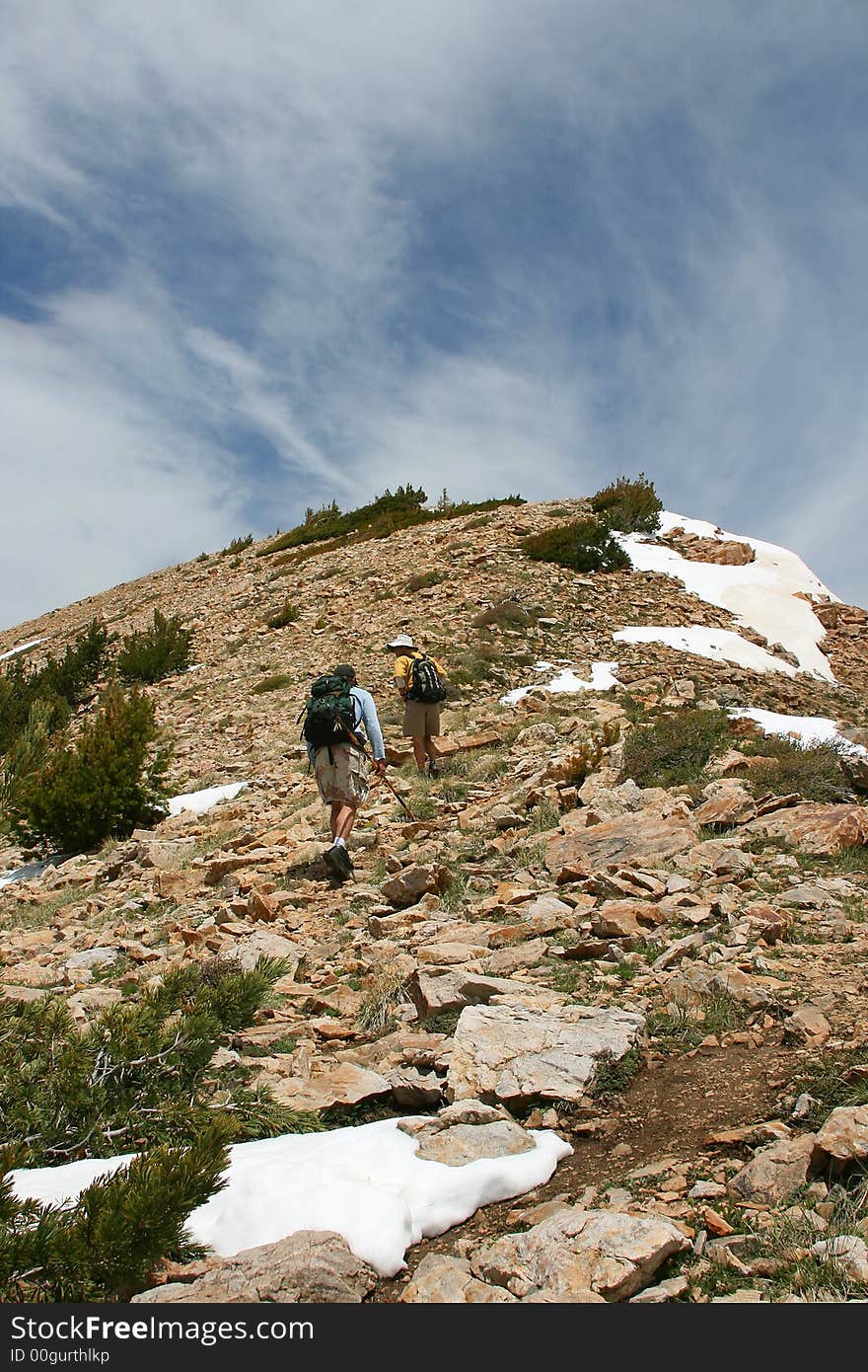 Two hikers go for the top of the mountain. Two hikers go for the top of the mountain