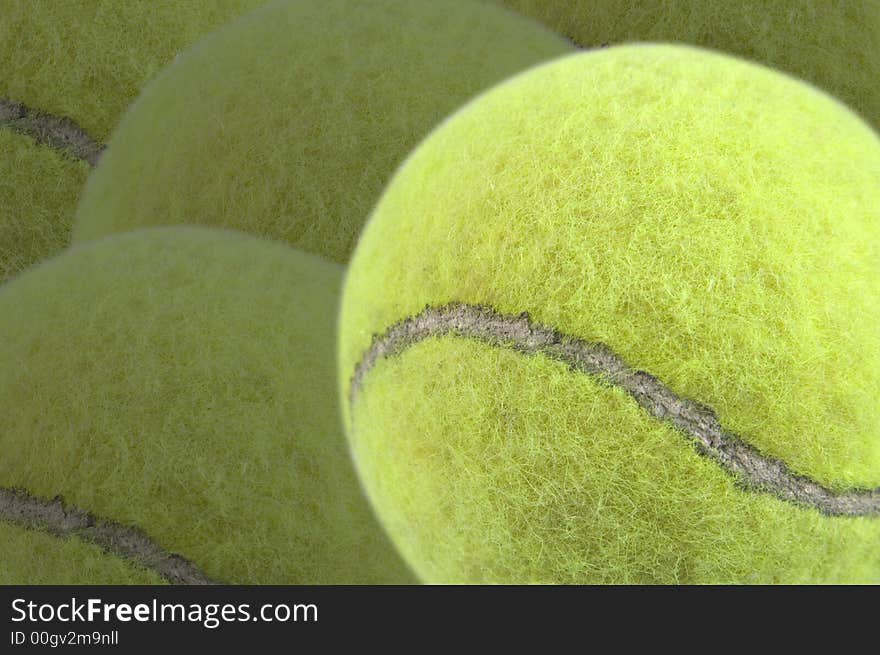 Tennis ball in foreground with more tennis balls as a darker background. Has clipping path for tennis ball