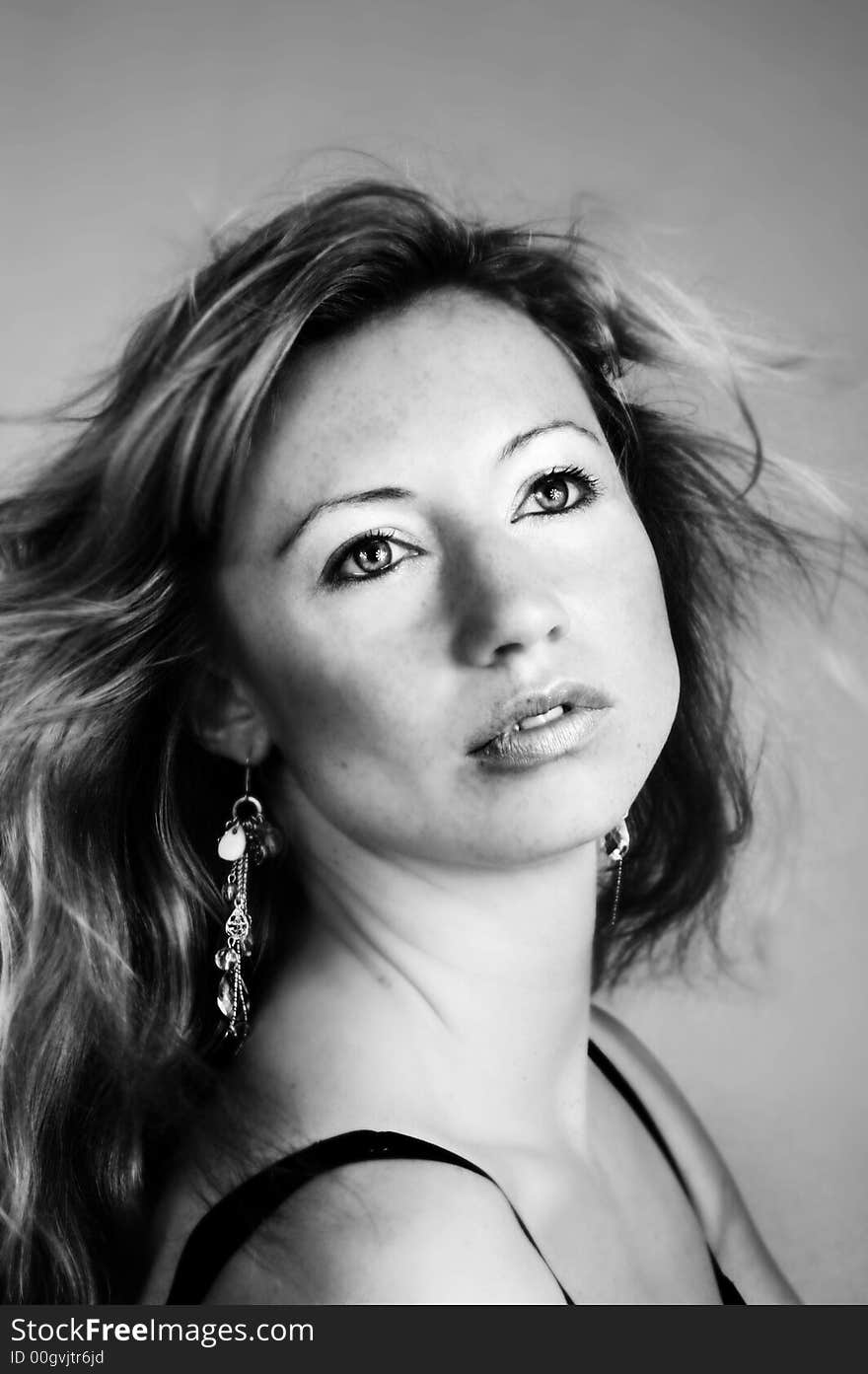 Beauty portrait of a woman with earrings and wind on her hair. Beauty portrait of a woman with earrings and wind on her hair