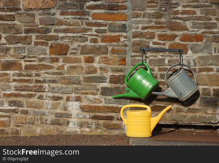 Three watering cans on the wall