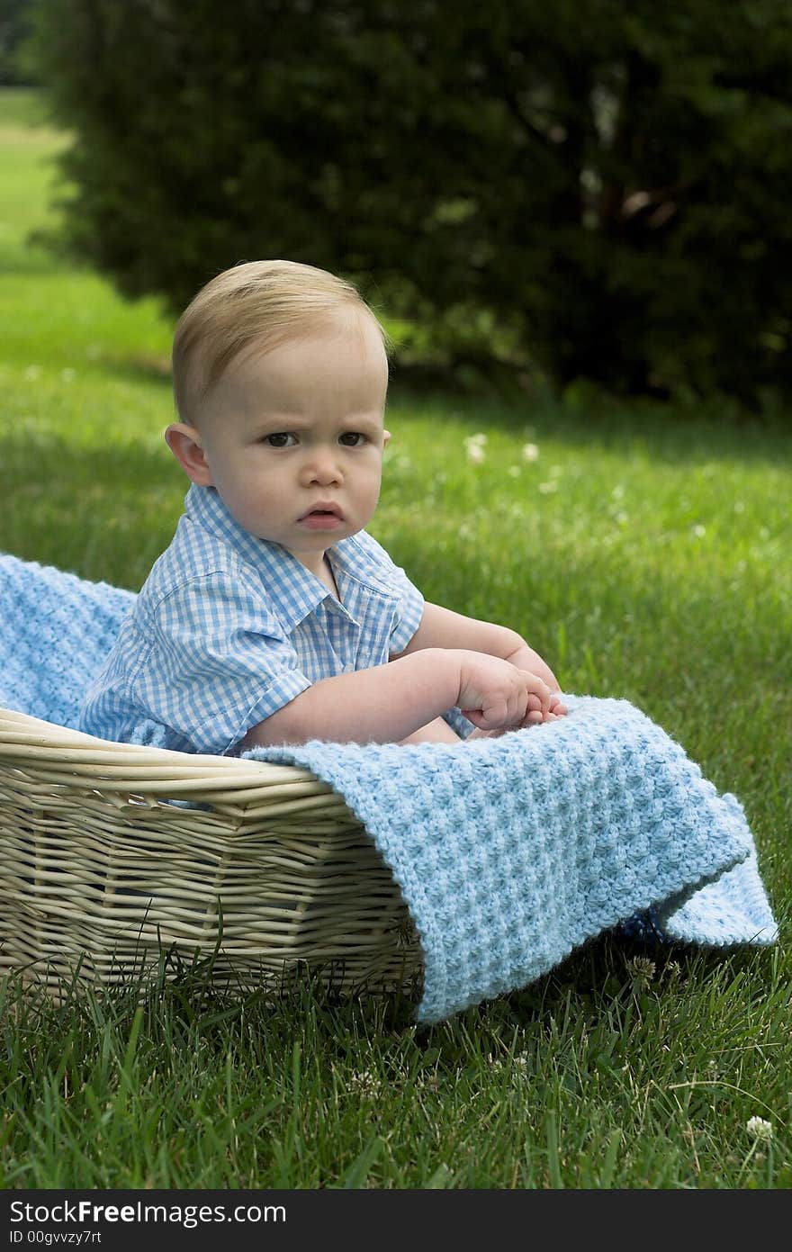 Image of beautiful toddler sitting in a basket in the grass. Image of beautiful toddler sitting in a basket in the grass