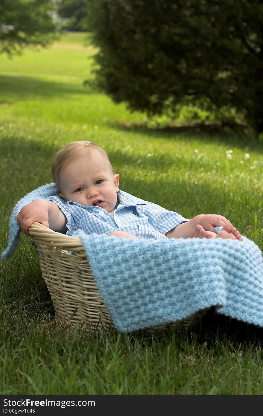 Image of beautiful toddler sitting in a basket in the grass. Image of beautiful toddler sitting in a basket in the grass