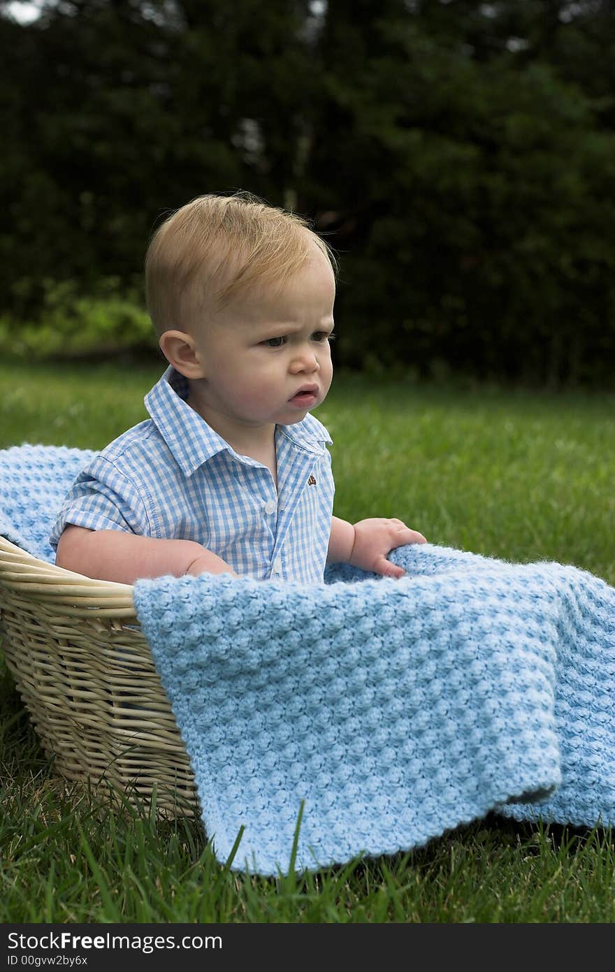 Image of beautiful toddler sitting in a basket in the grass. Image of beautiful toddler sitting in a basket in the grass