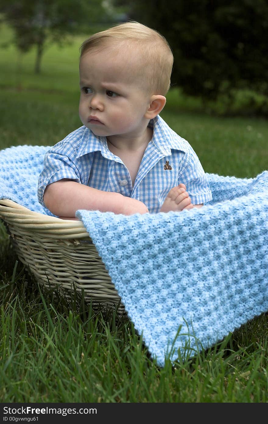 Image of beautiful toddler sitting in a basket in the grass. Image of beautiful toddler sitting in a basket in the grass