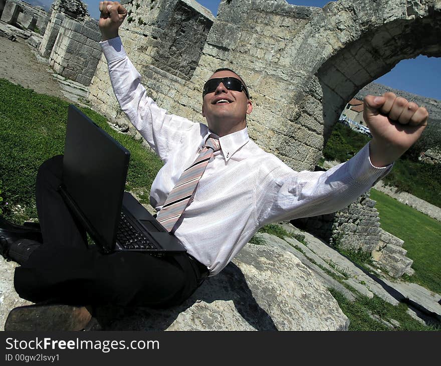 Smiling young businessman with laptop.