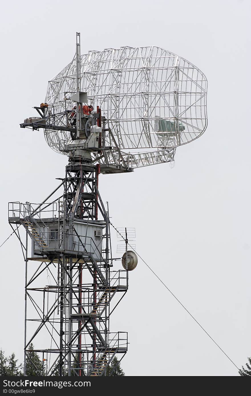 Middle distance view of a radar dish gleaming silver in the hazy light of the afternoon sun. Middle distance view of a radar dish gleaming silver in the hazy light of the afternoon sun