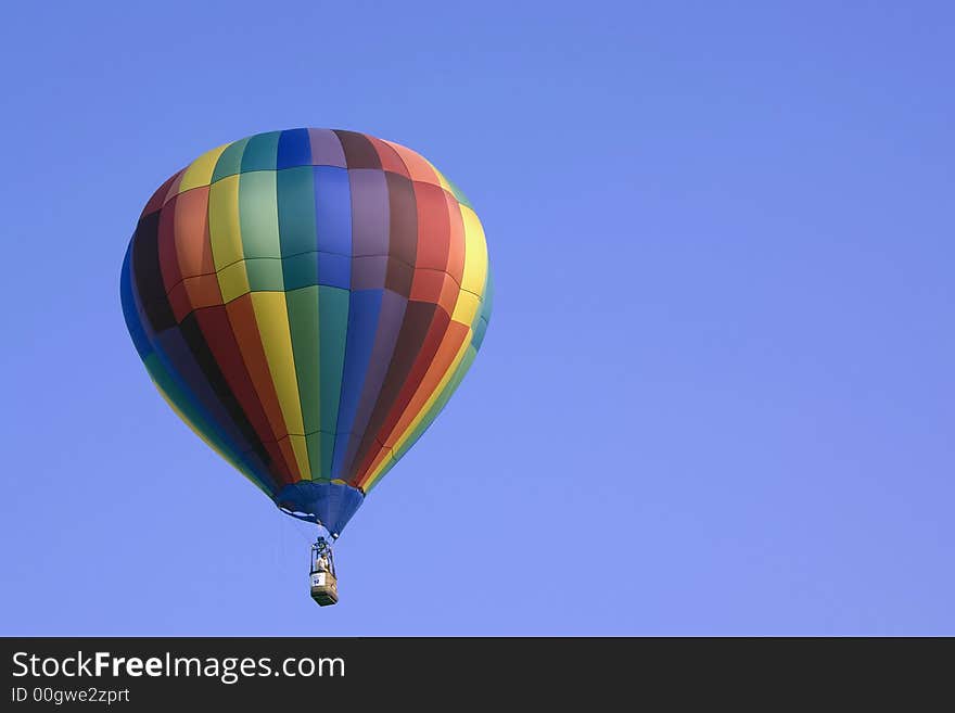 Here is a photo of a colorful hot air balloon floating peacefully in the sky with a beautiful blue backround