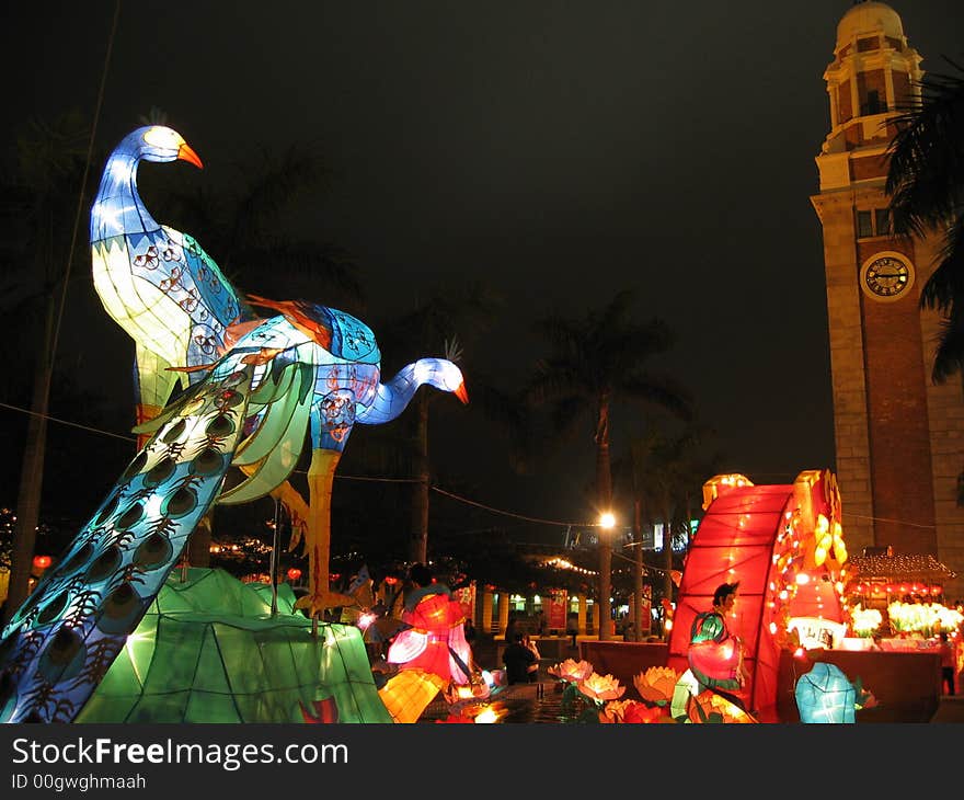 Couple of illuminated from within peafowls behind clock tower. Couple of illuminated from within peafowls behind clock tower