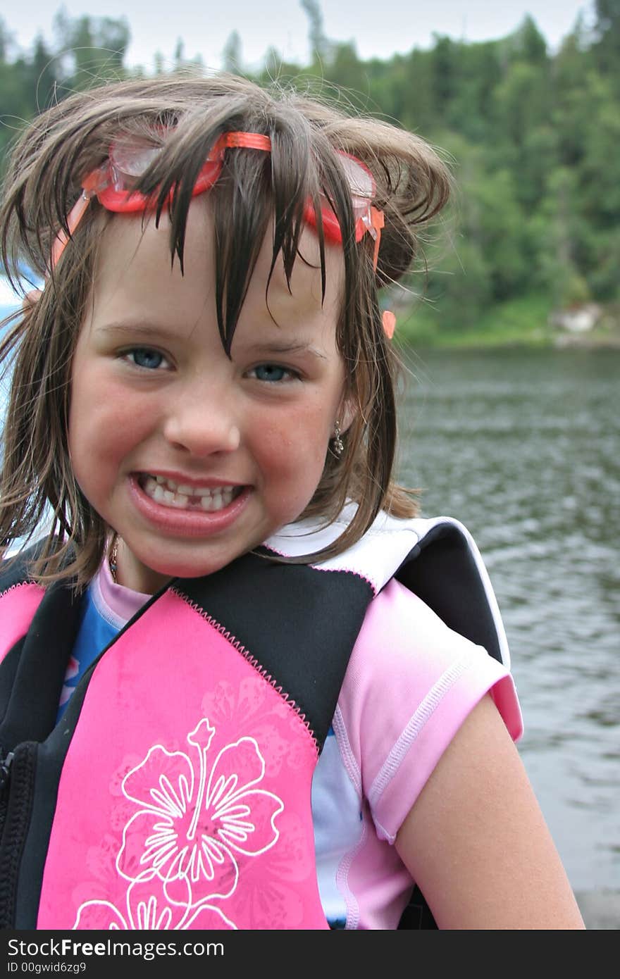 Young pretty girl wearing swimming goggles and life jacket at lake. Young pretty girl wearing swimming goggles and life jacket at lake