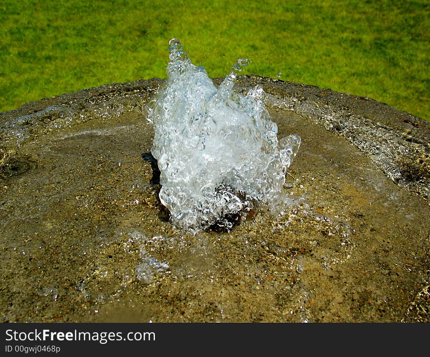 A fountain in concrete with grass behind. A fountain in concrete with grass behind.