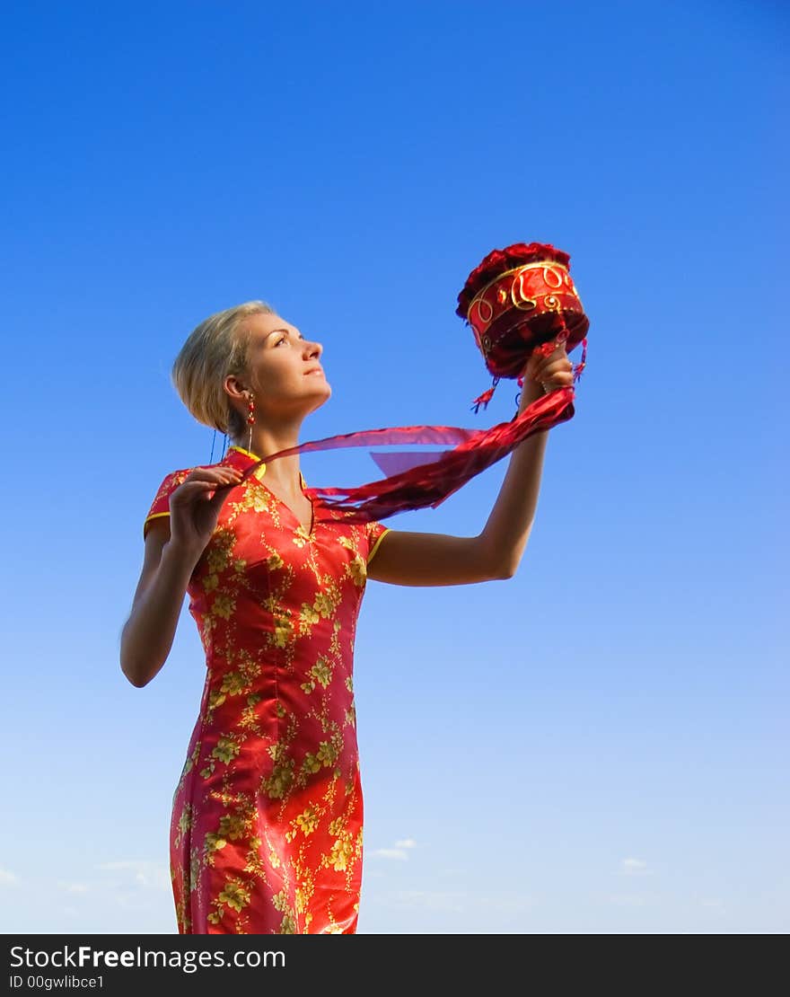 Beautiful blond girl with a bouquet of red roses over crystal clear blue sky